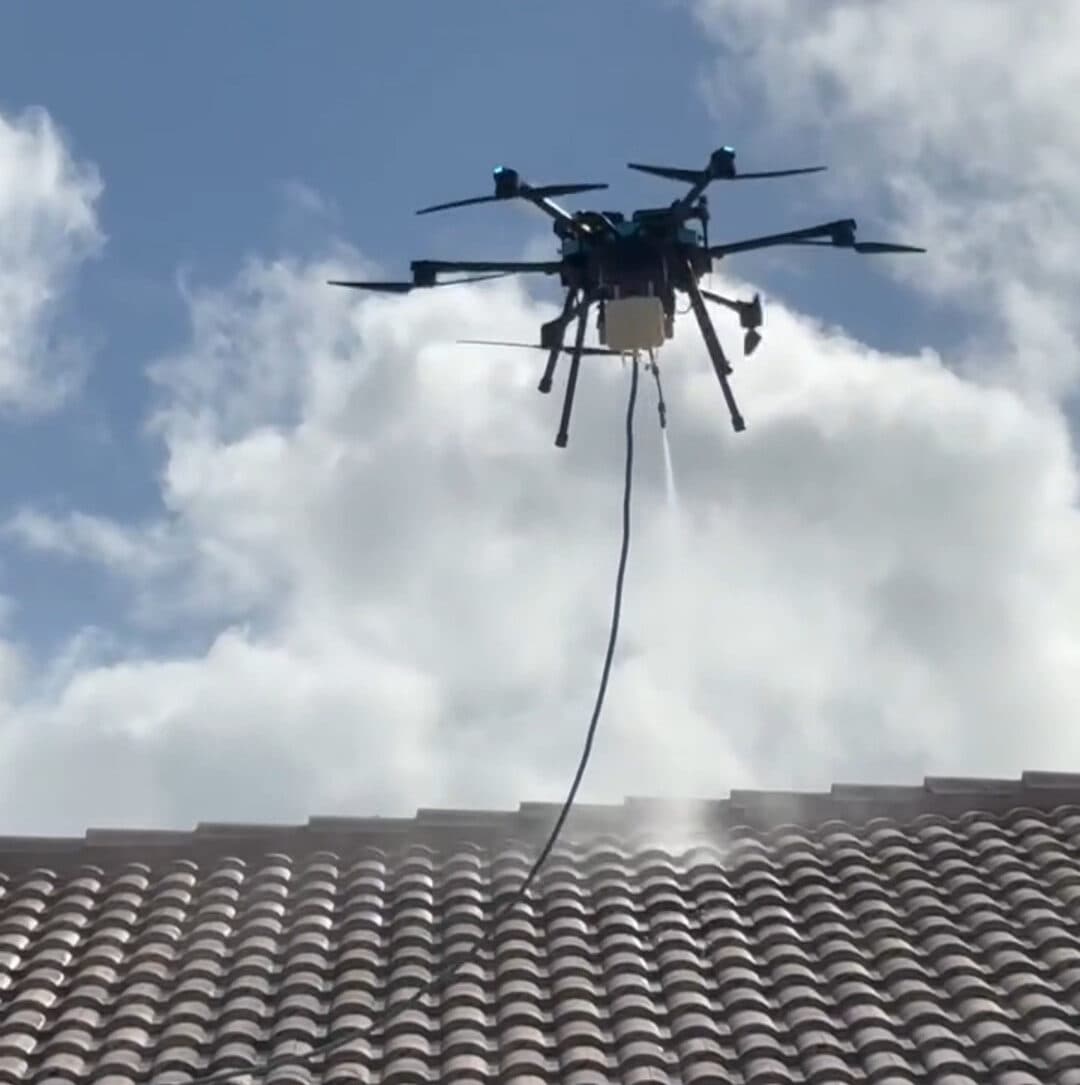 Drone soft-washing a roof from the ground